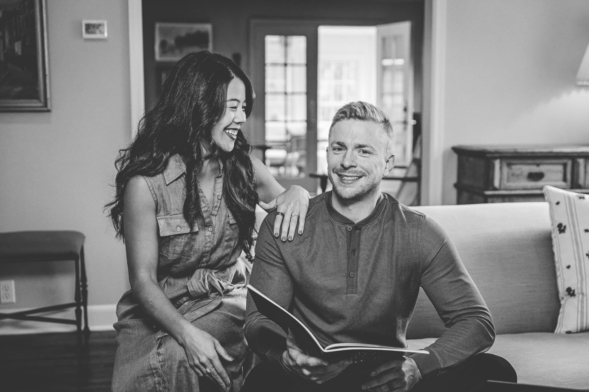 CJ and Katy Norman sitting together on a couch reviewing a book
