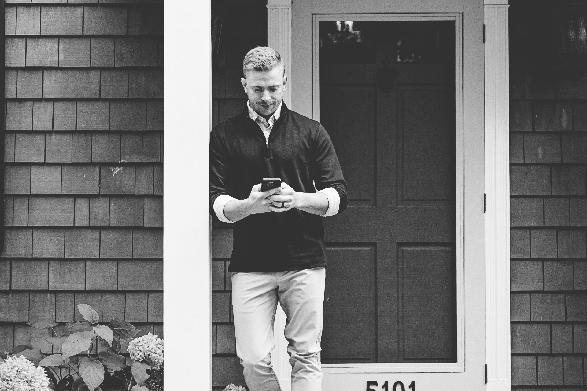 CJ Norman on a front porch checking his phone